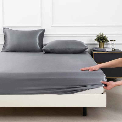 Drap housse gris satiné mains mise en place coin