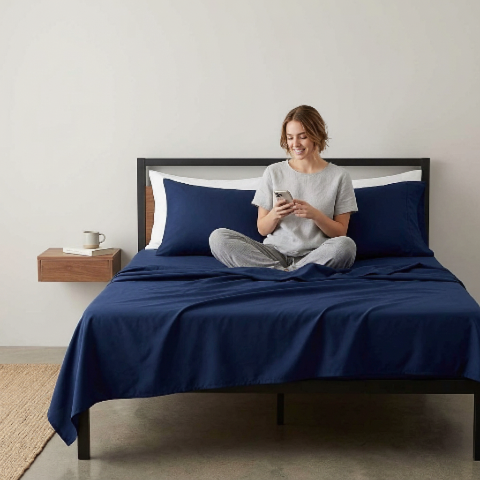 Draps de lit marine femme assise regarde portable