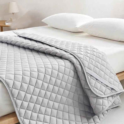 Protège matelas imperméable gris déposé couverture sur lit