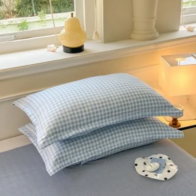 Taie d'oreiller bleu vichy empilée sur lit
