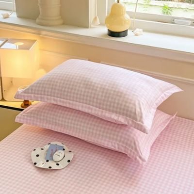 Taie d'oreiller rose vichy empilée sur lit