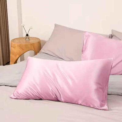 Taies d oreiller en satin rose sur lit